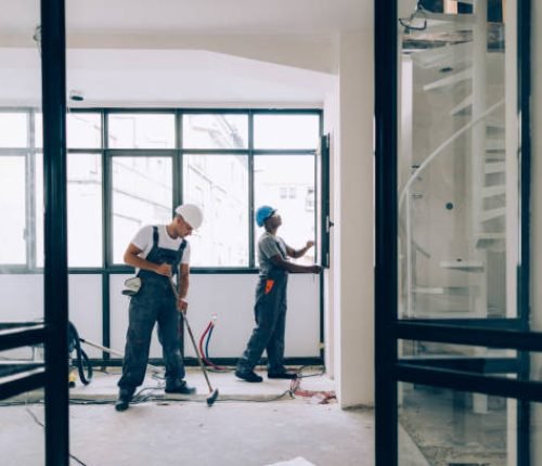Two colleagues doing construction work together in an unfinished building.